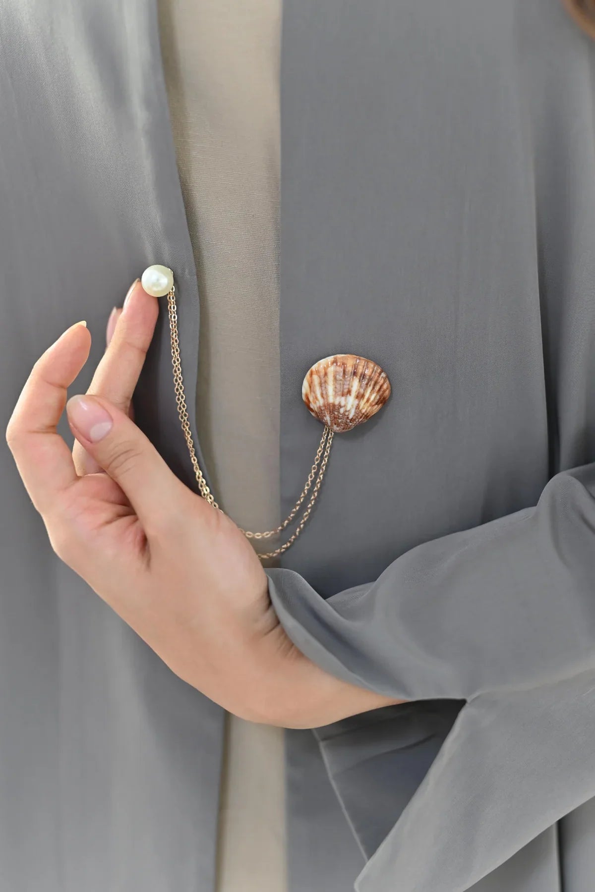 NASAB Accessories collection featuring Dana shell and pearl chain brooch on grey abaya